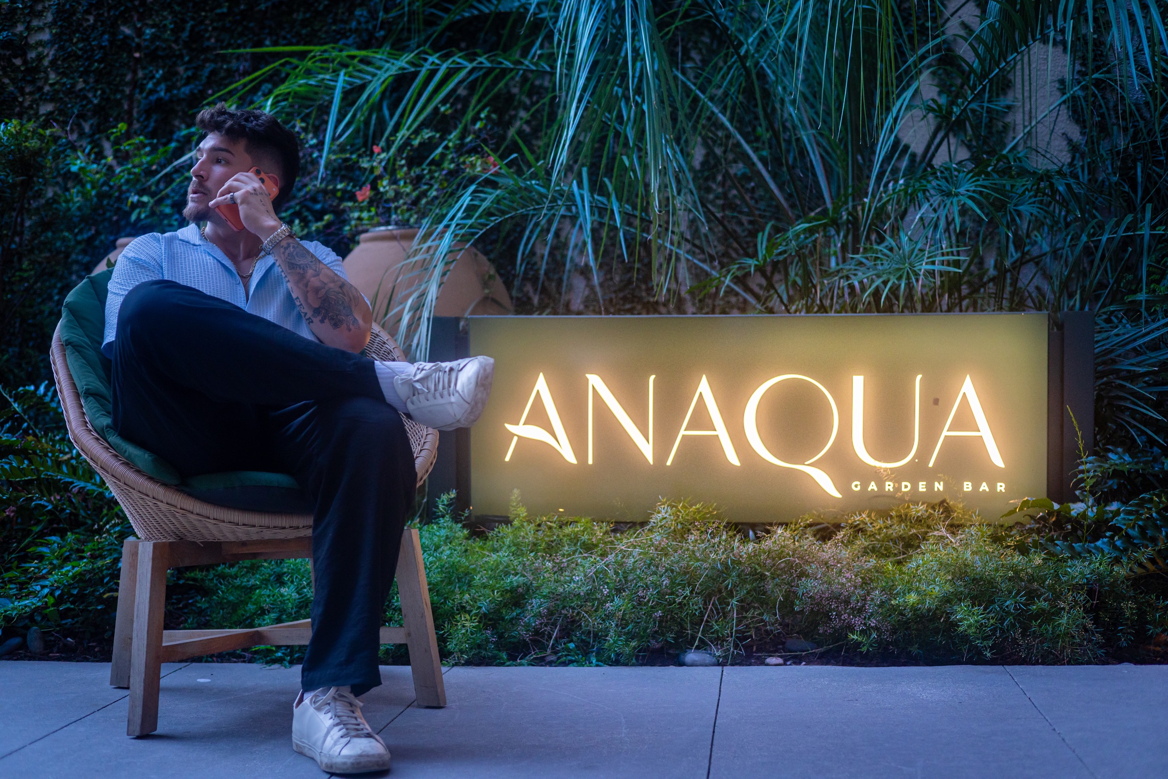 Rilan Quinones seated beside the Anaqua Garden Bar sign